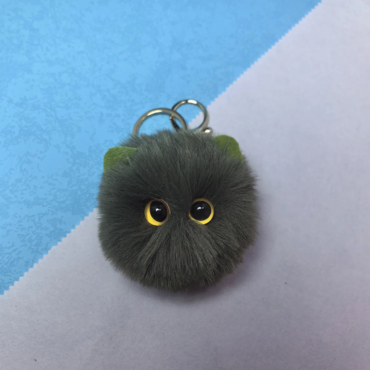 Plush keychain with large eyes on a blue and white background