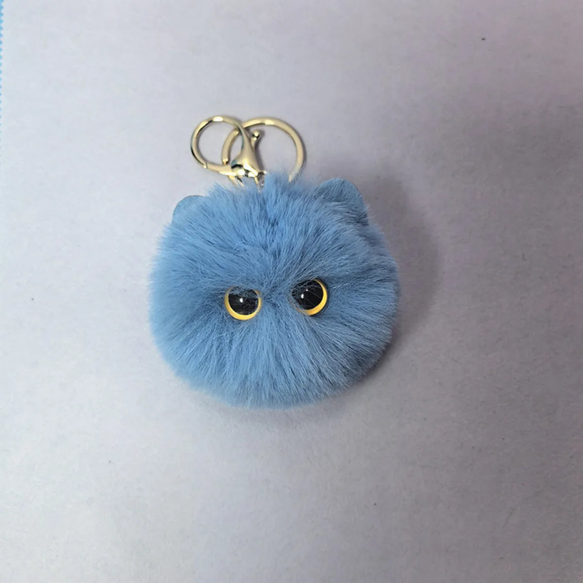Blue fluffy keychain with gold rings on a light gray background