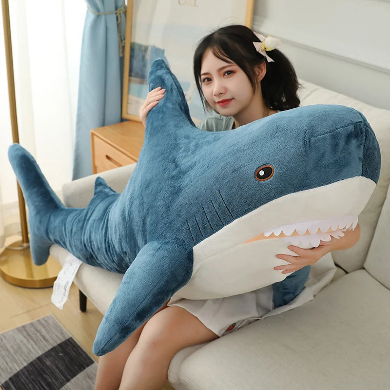 Person holding a large shark-shaped pillow on a couch