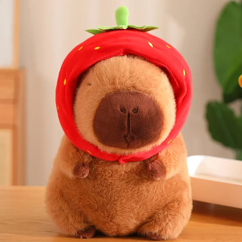 Plush toy resembling a bear wearing a strawberry hat on a wooden surface.