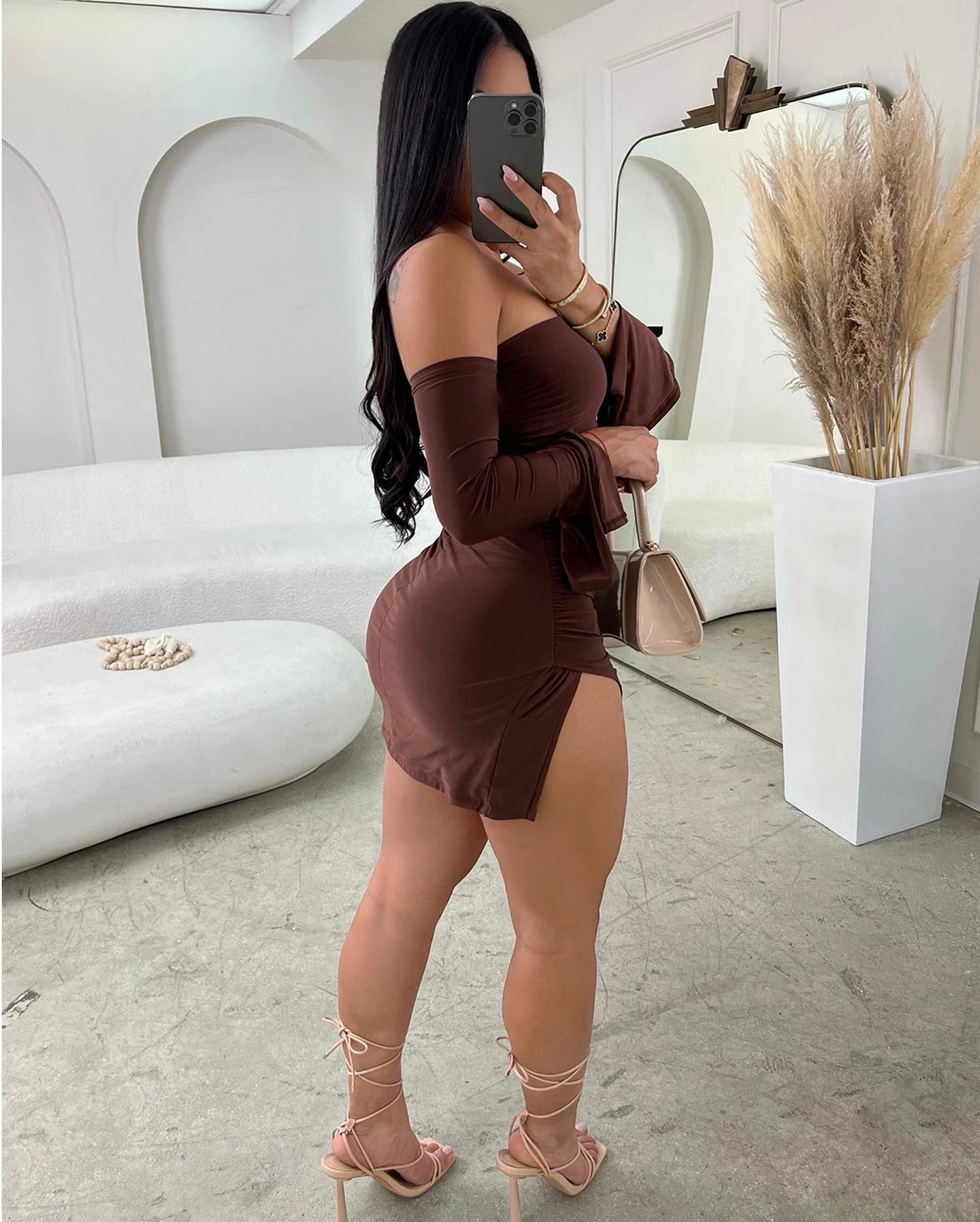 Woman in a brown dress taking a mirror selfie in a stylish room.
