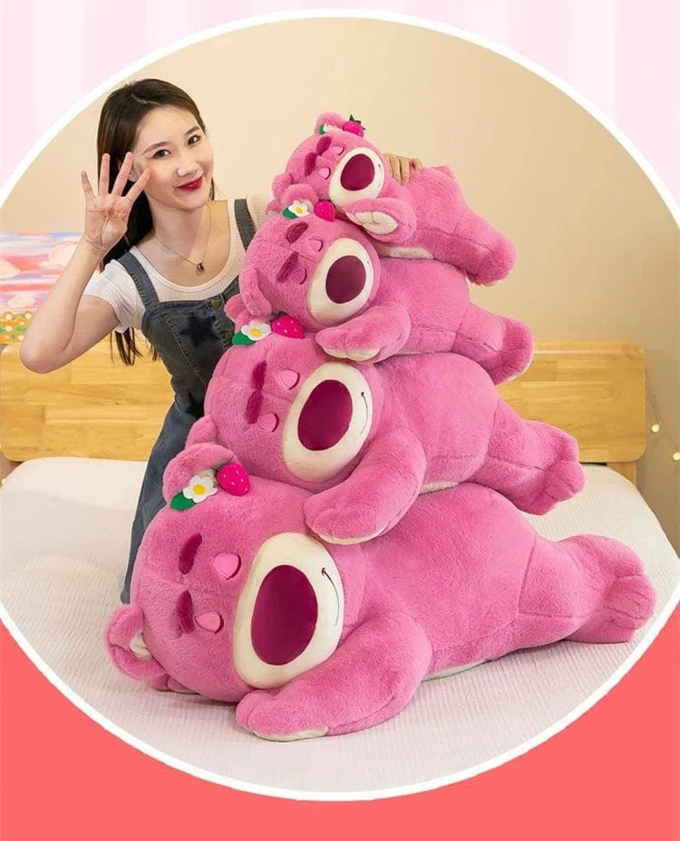 Stack of pink plush toys resembling bears with a person next to them on a light-colored surface.