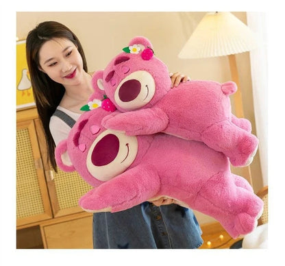 Person holding a large pink teddy bear with a smiling face in a room setting.