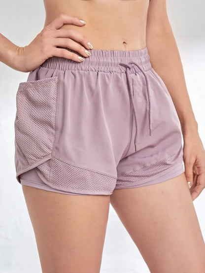 Light purple athletic shorts with mesh panels on a white background