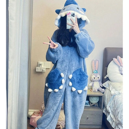 Person wearing a blue shark onesie in a bedroom setting.