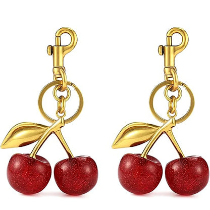 Gold cherry-shaped keychains with red stones on a white background