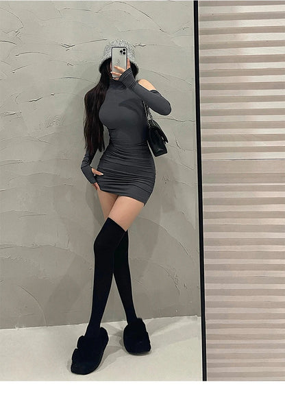 Person wearing a black dress and knee-high boots taking a mirror selfie.