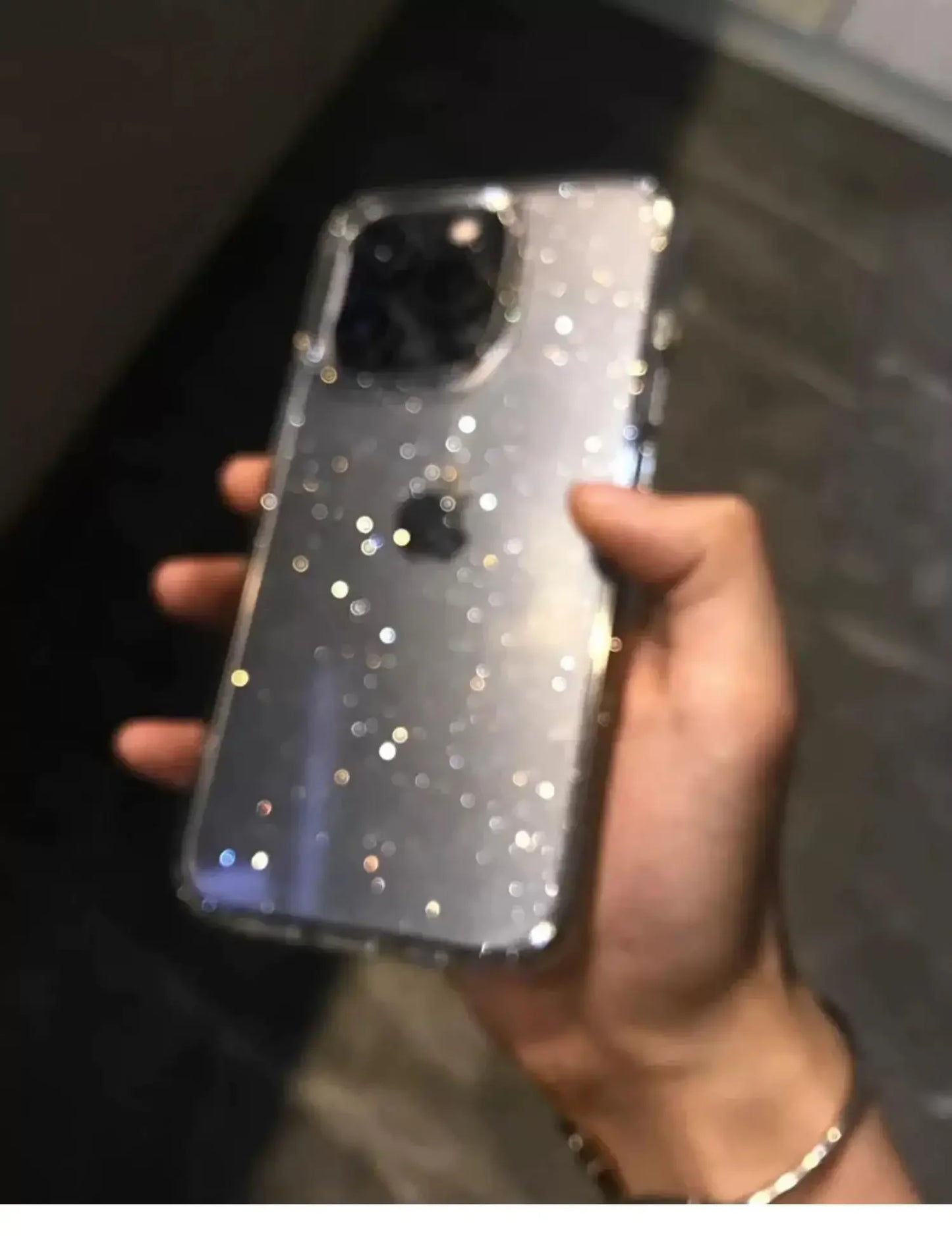 Hand holding a phone with a glittery case against a blurred background