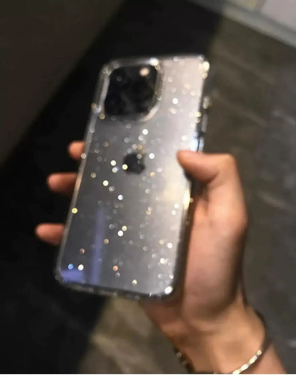 Hand holding a phone with a glittery case against a blurred background