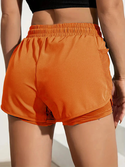 Orange athletic shorts worn by a person on a neutral background