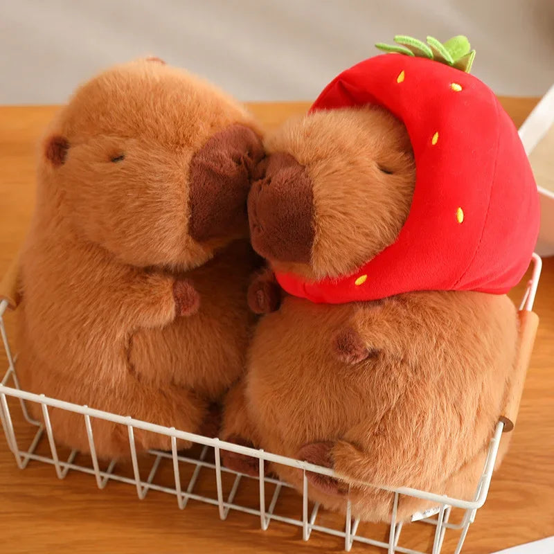 Two plush toys, one brown and one wearing a strawberry hat, in a white basket on a wooden surface.