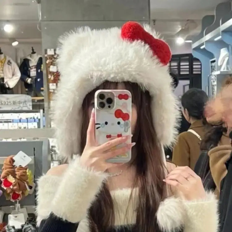 Person wearing a fluffy white hood with red accents, holding a phone with a Hello Kitty case in a store setting.