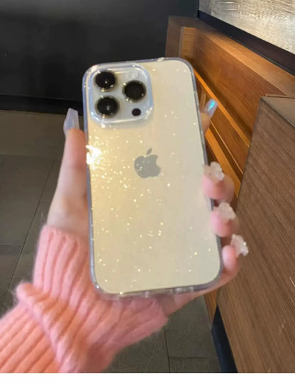 Hand holding a phone with a glittery case, blurred indoor background