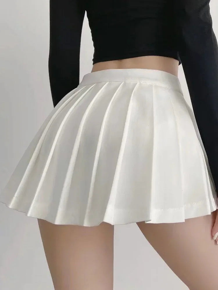 White pleated skirt worn with a black long-sleeve top on a plain background