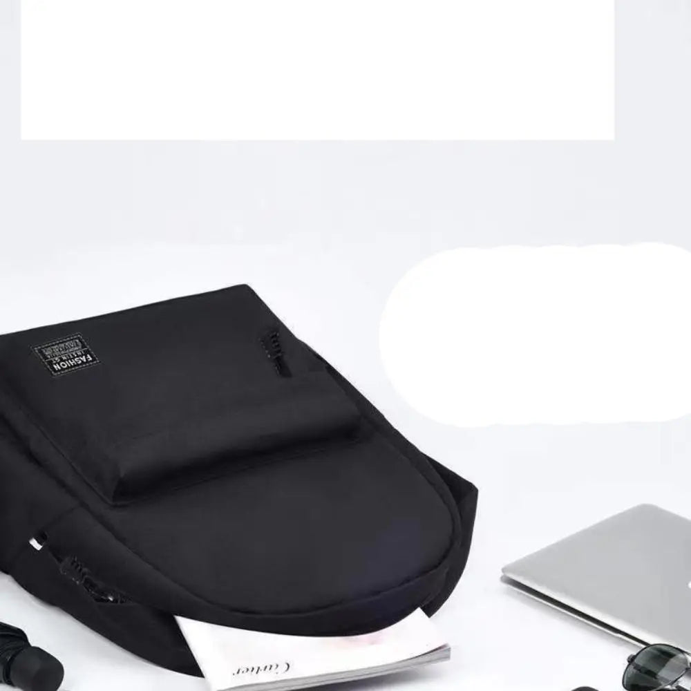 Black backpack on a white surface with a laptop and other items.