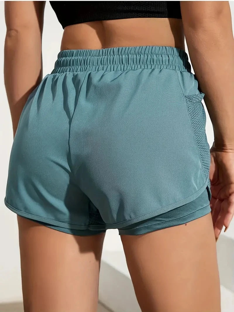 Teal athletic shorts worn by a person on a plain background