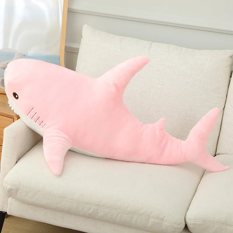 Pink shark-shaped pillow on a beige couch