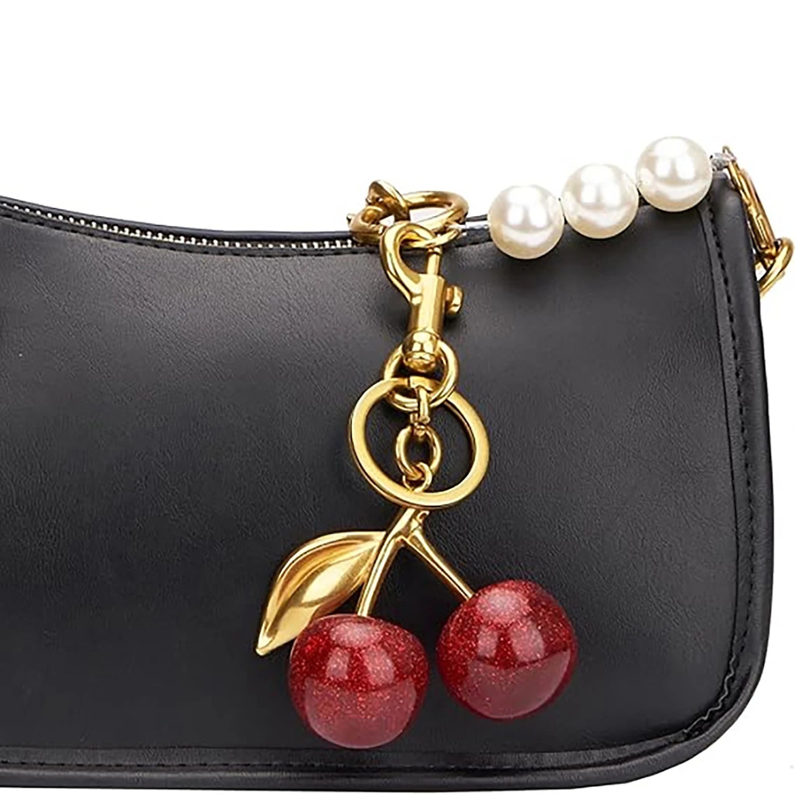 Black handbag with a cherry charm and pearl strap on a white background