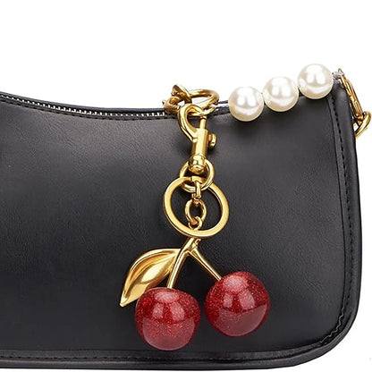Black handbag with a cherry charm and pearl strap on a white background