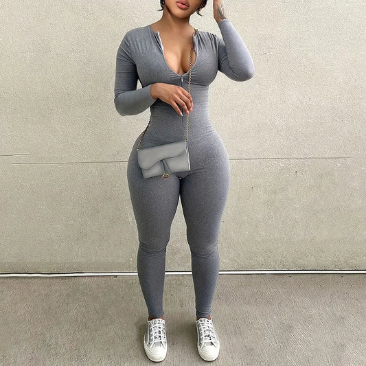Person wearing a gray bodysuit with white sneakers against a plain background