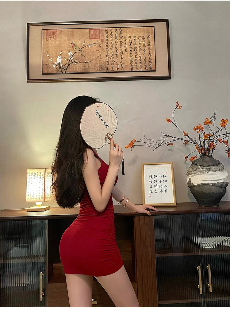 Woman in a red dress holding a fan in a room with decorative elements.