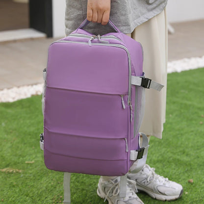 Purple backpack with gray straps held by a person on grass