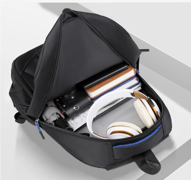 Black backpack with compartments containing electronic devices on a light gray background