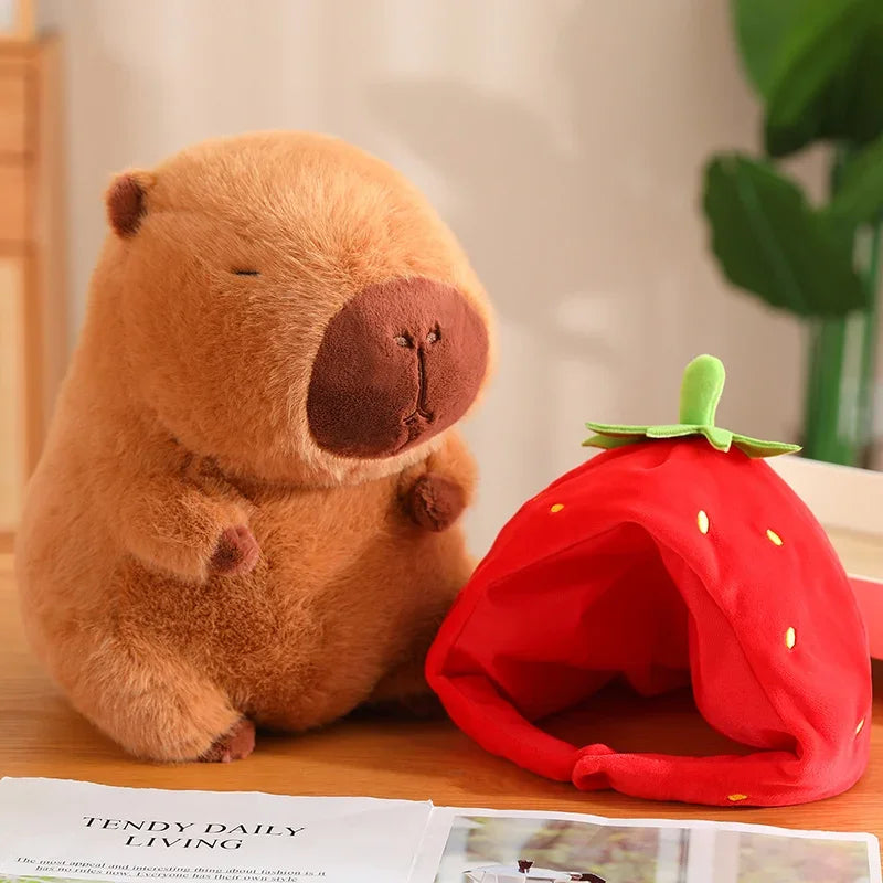 Plush bear toy next to a red strawberry-shaped pet bed on a table.