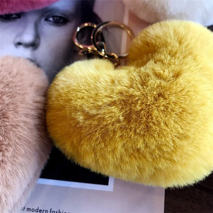 Yellow fluffy heart-shaped keychain held by a person with a blurred background