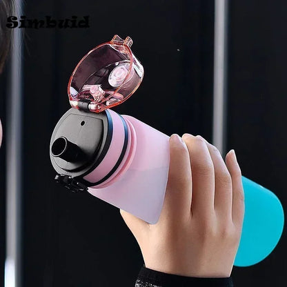 Hand holding a pink and black device with a light on a dark background