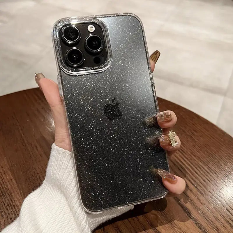 Phone case with glittery finish held by a hand on a wooden surface