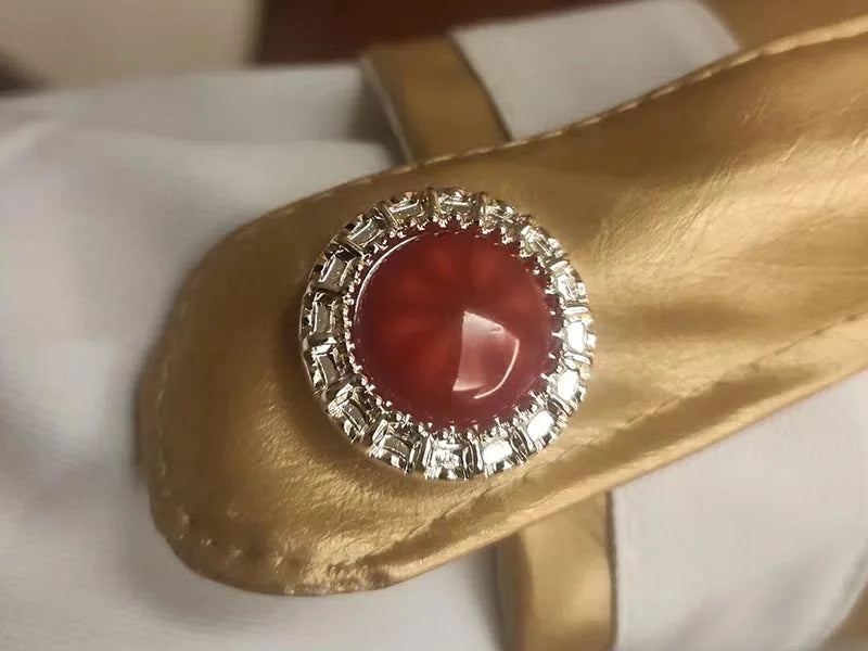 Gold bracelet with a red gemstone and silver accents on a white background