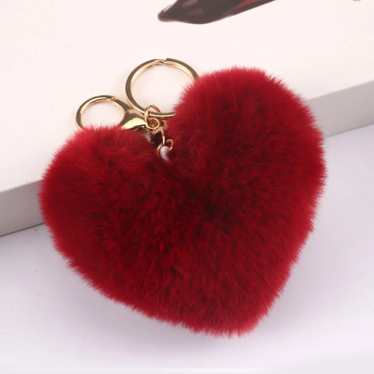 Red heart-shaped fluffy keychain with a gold ring on a white background