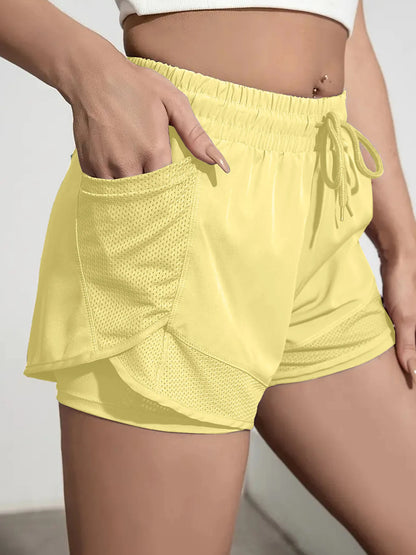 Yellow athletic shorts worn by a person on a neutral background
