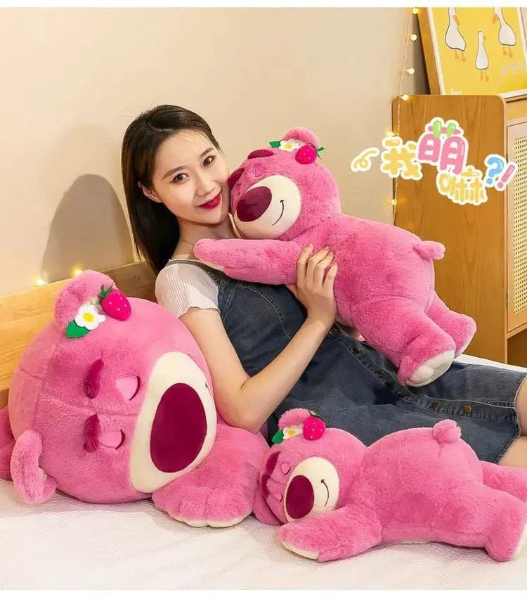 Woman holding a large pink plush toy with a smiley face on a light-colored floor.